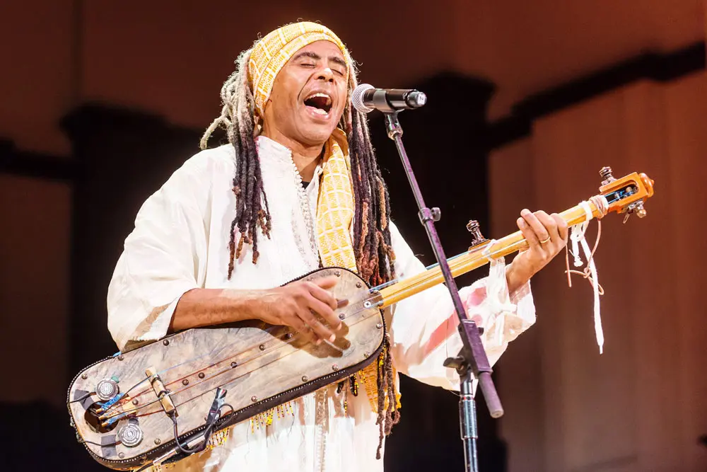 Hassan Hakmoun performing on a large international festival stage surrounded by his ensemble