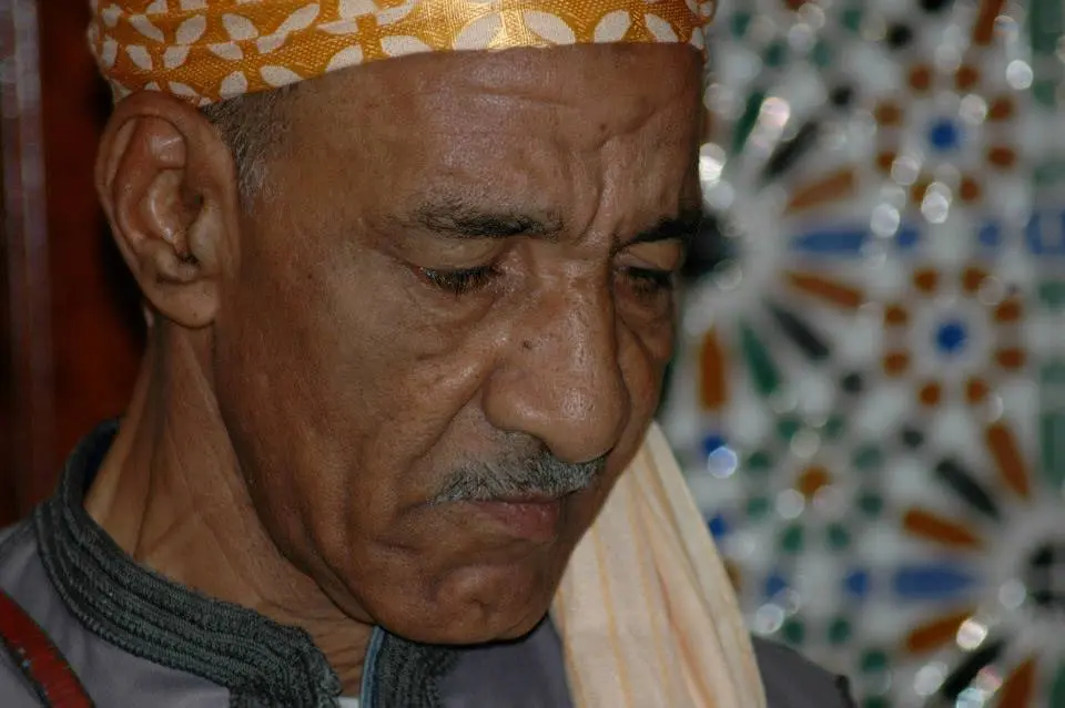 Makhzoumi's hands applying the Qriss technique -- close-up of the guembri neck and skin